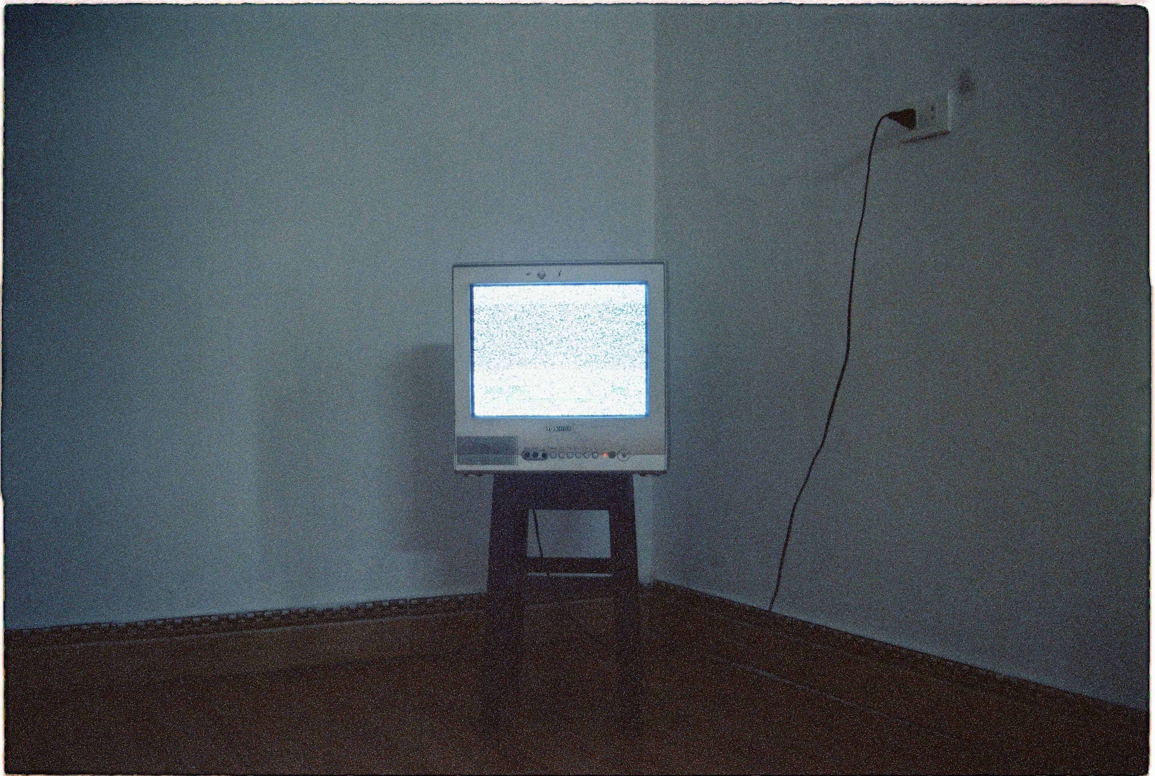 A dim living room with a television glow and a closed Bible on a table.